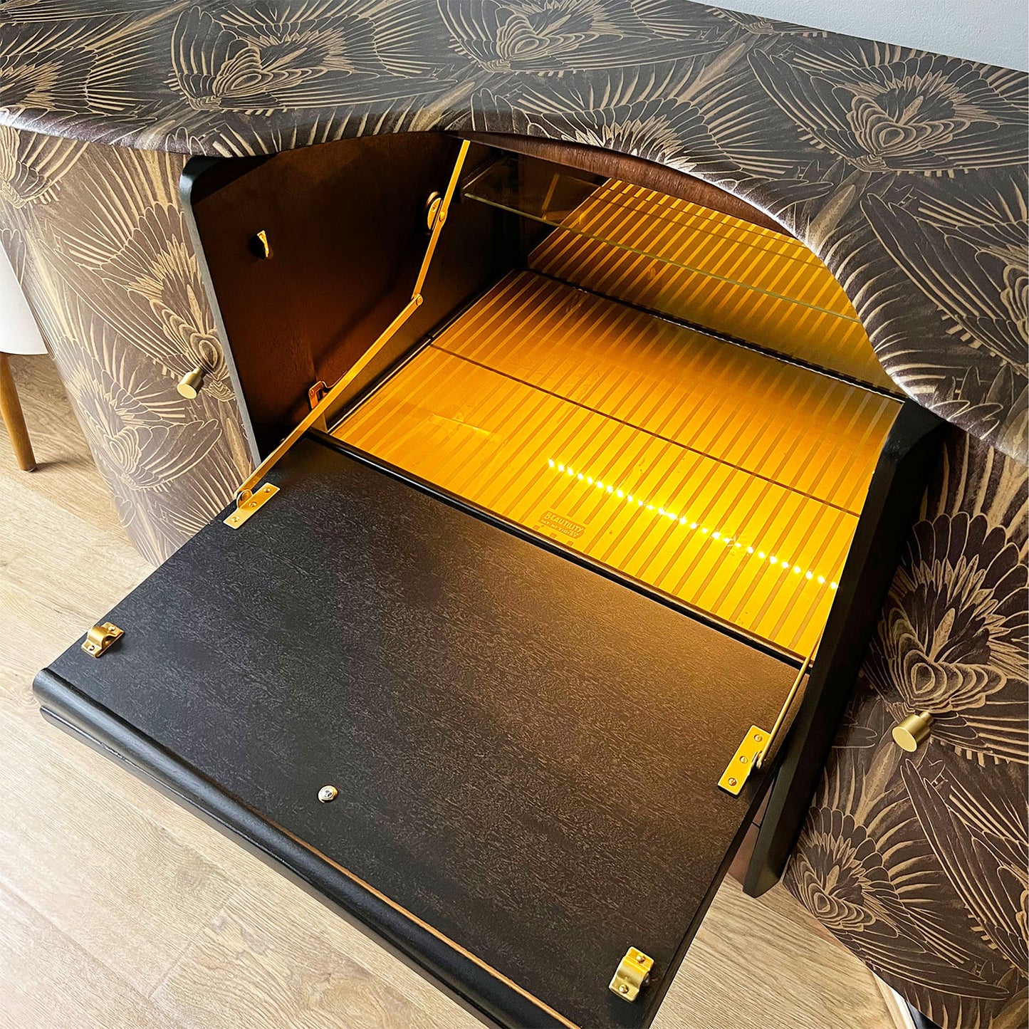 Motion sensor LED light inside Beautility cocktail cabinet, highlighting glassware storage and mirrored cocktail prep area.