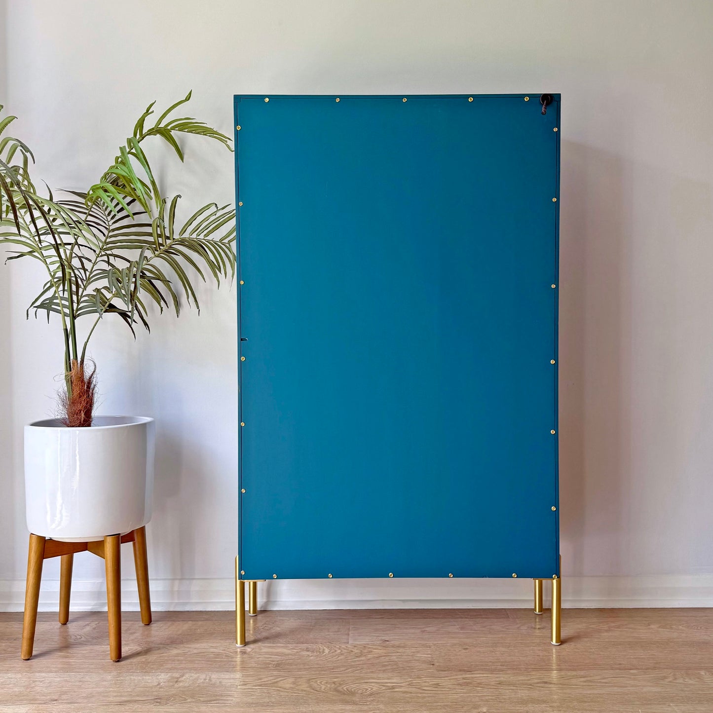 Back of a mid-century modern G Plan cabinet refinished in teal blue, highlighting the smooth paint finish and brass fixings.