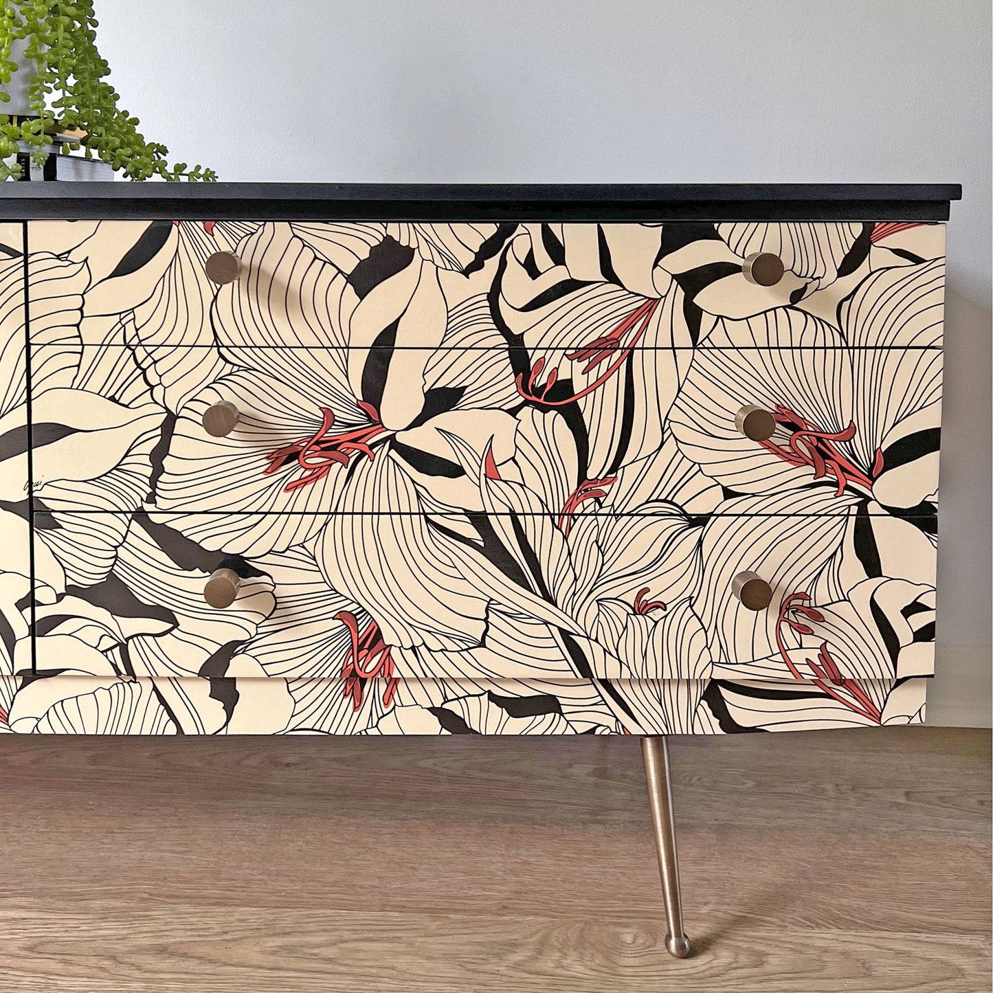 Close-up of Beautility sideboard drawer fronts, featuring Gucci 'Lilies' cream and black decoupage with antiqued brass handles for a luxurious finish.