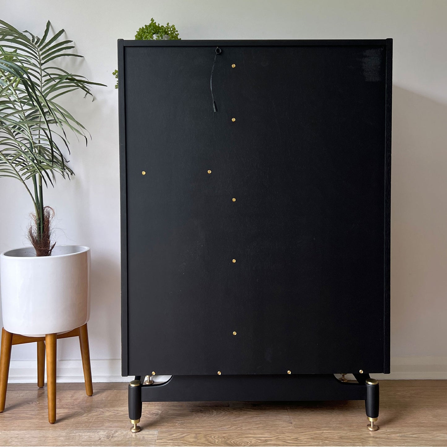 Back view of the G Plan Librenza drinks cabinet, painted in sleek black with polished brass screws and cups for a refined, high-end finish.