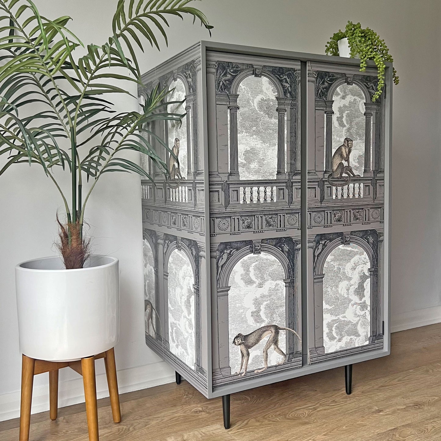 ide profile of a bespoke John & Sylvia Reid Stag C Range drinks cabinet, showcasing its sleek black tapered legs and seamless Fornasetti 'Procuratie con Vista' design wrapping around the exterior."