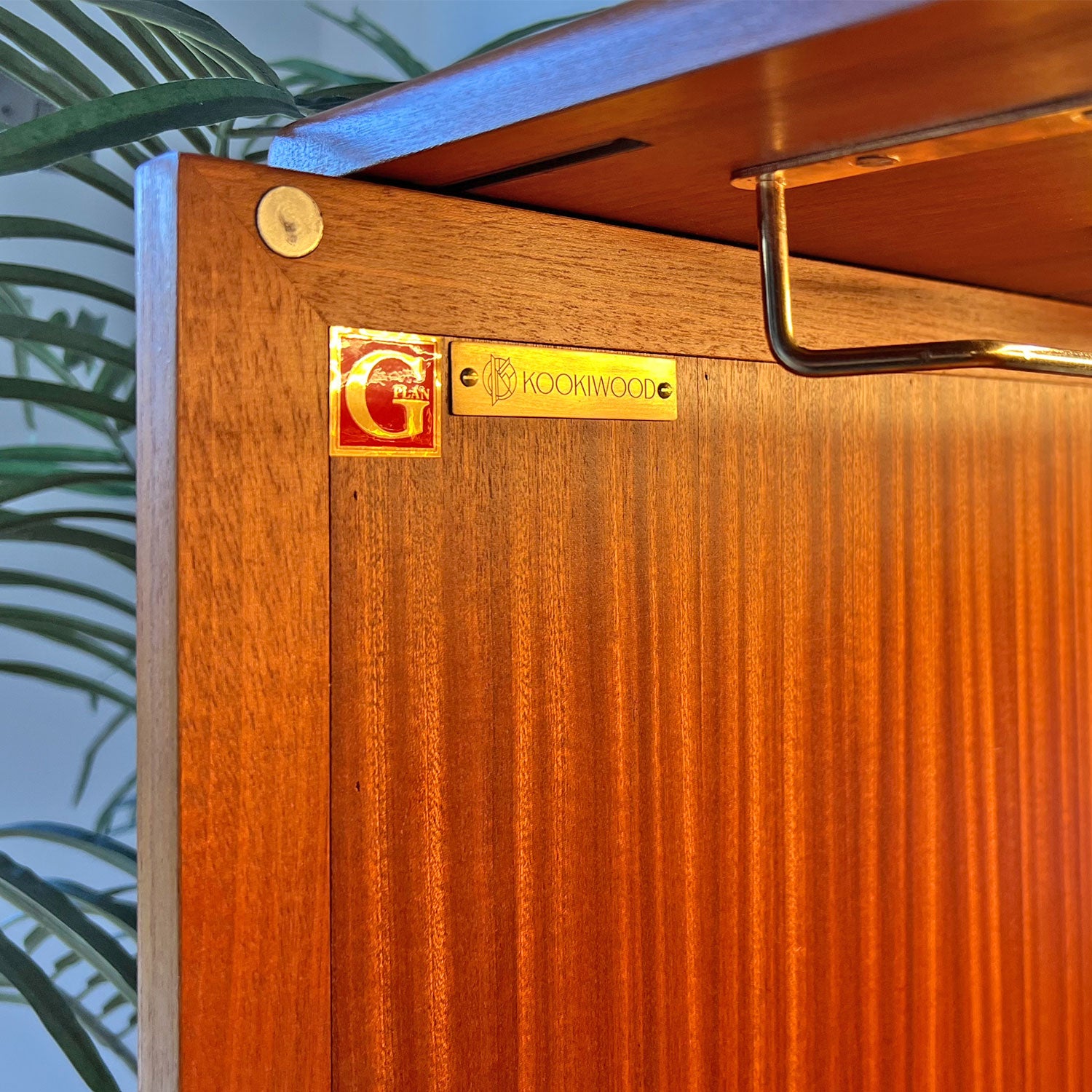 A close-up of the authentic G Plan Fresco drinks cabinet badge alongside Kookiwood branding, showcasing expert craftsmanship and meticulous restoration.