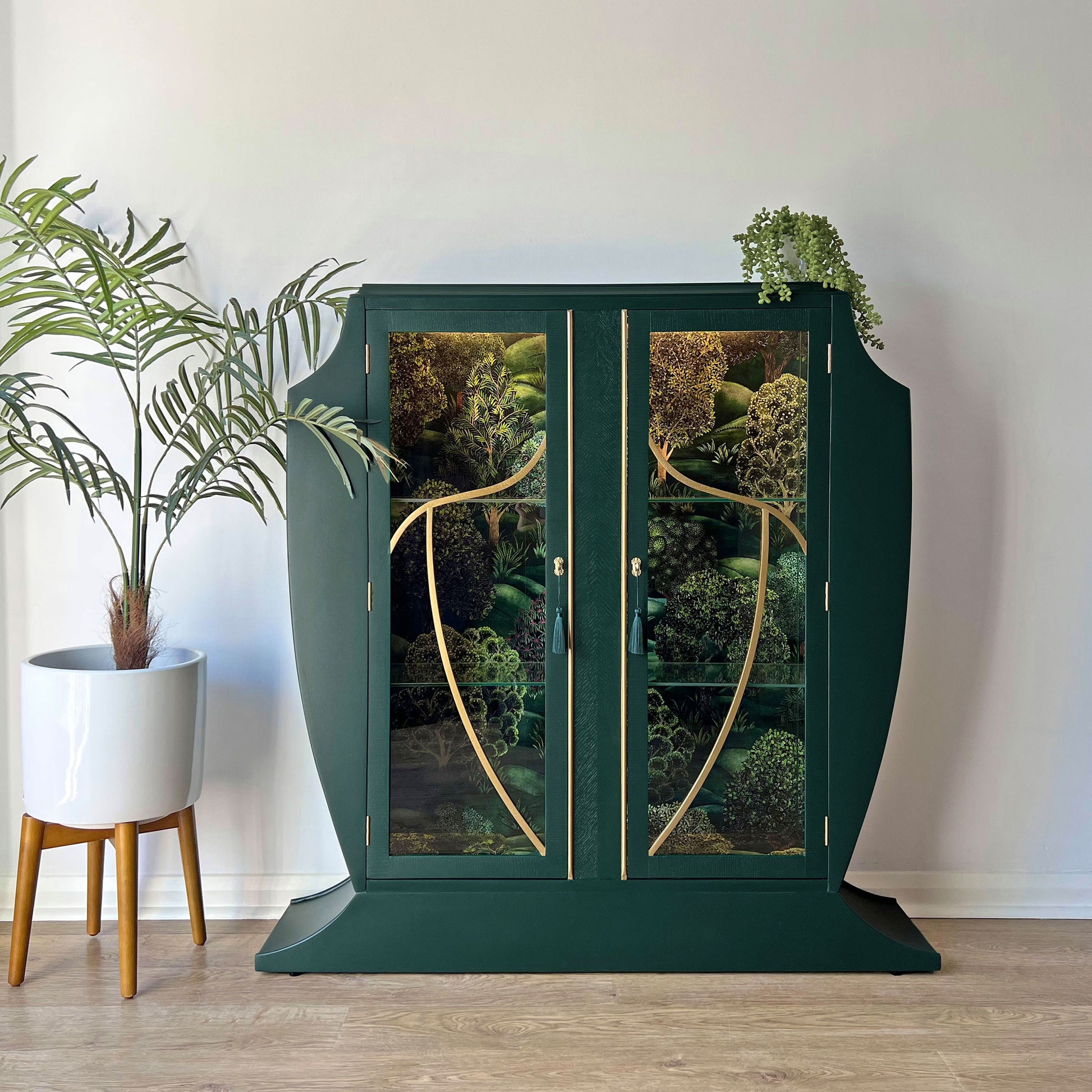 Hand-painted green Art Deco drinks cabinet with illuminated Cole & Son forest-themed interior.