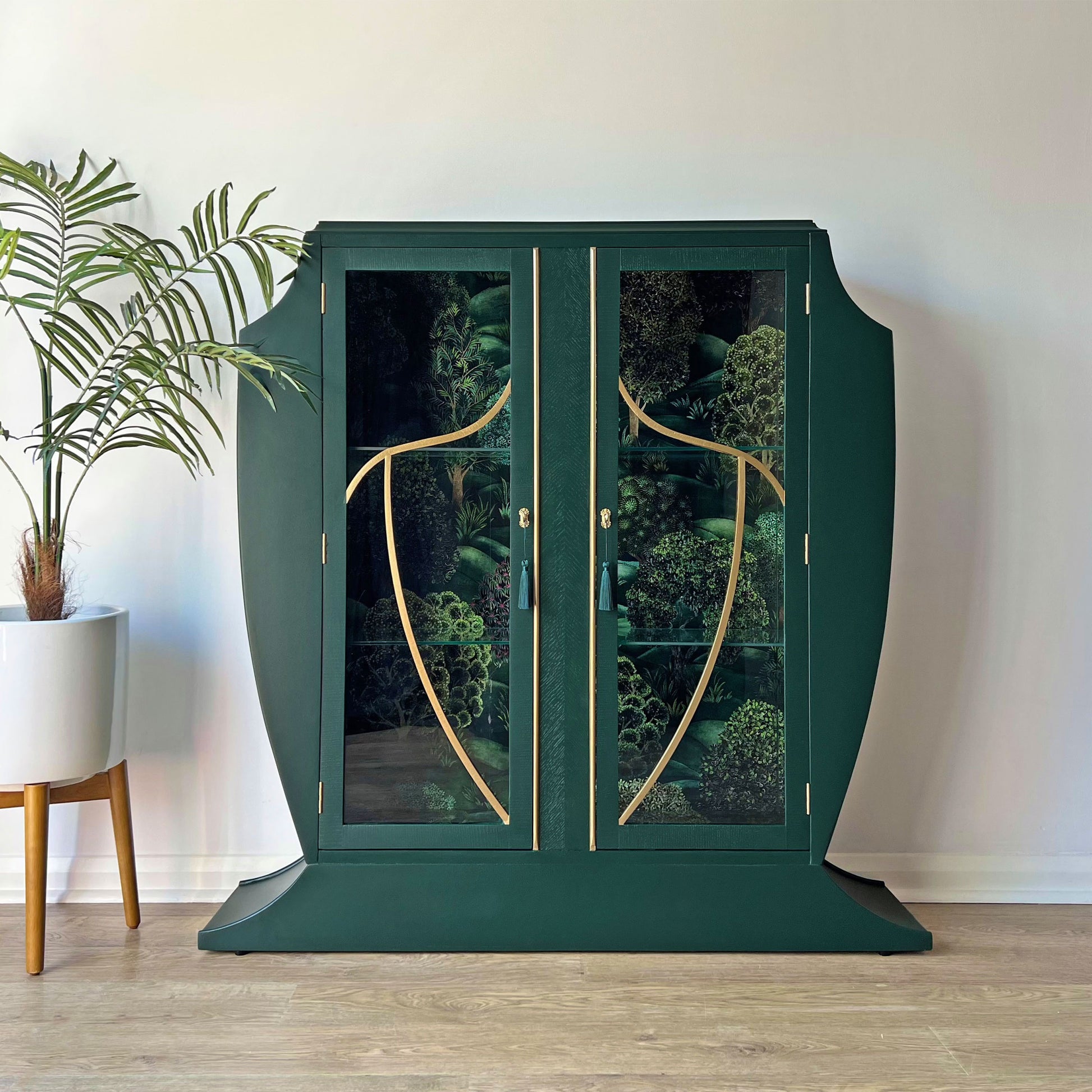 Front view of closed green Art Deco cocktail cabinet featuring glass doors and Cole & Son Forest design backing.