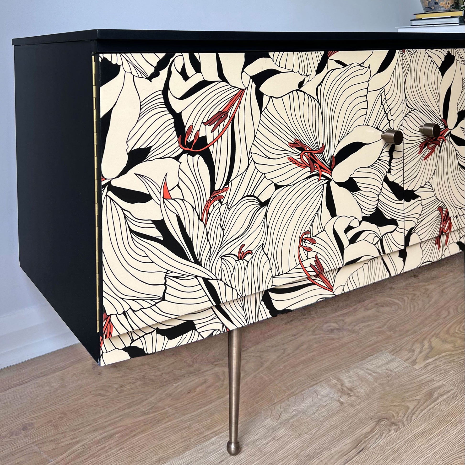 Side profile of Beautility sideboard, showcasing black painted sides, Gucci 'Lilies' decoupage, and antiqued brass accents.