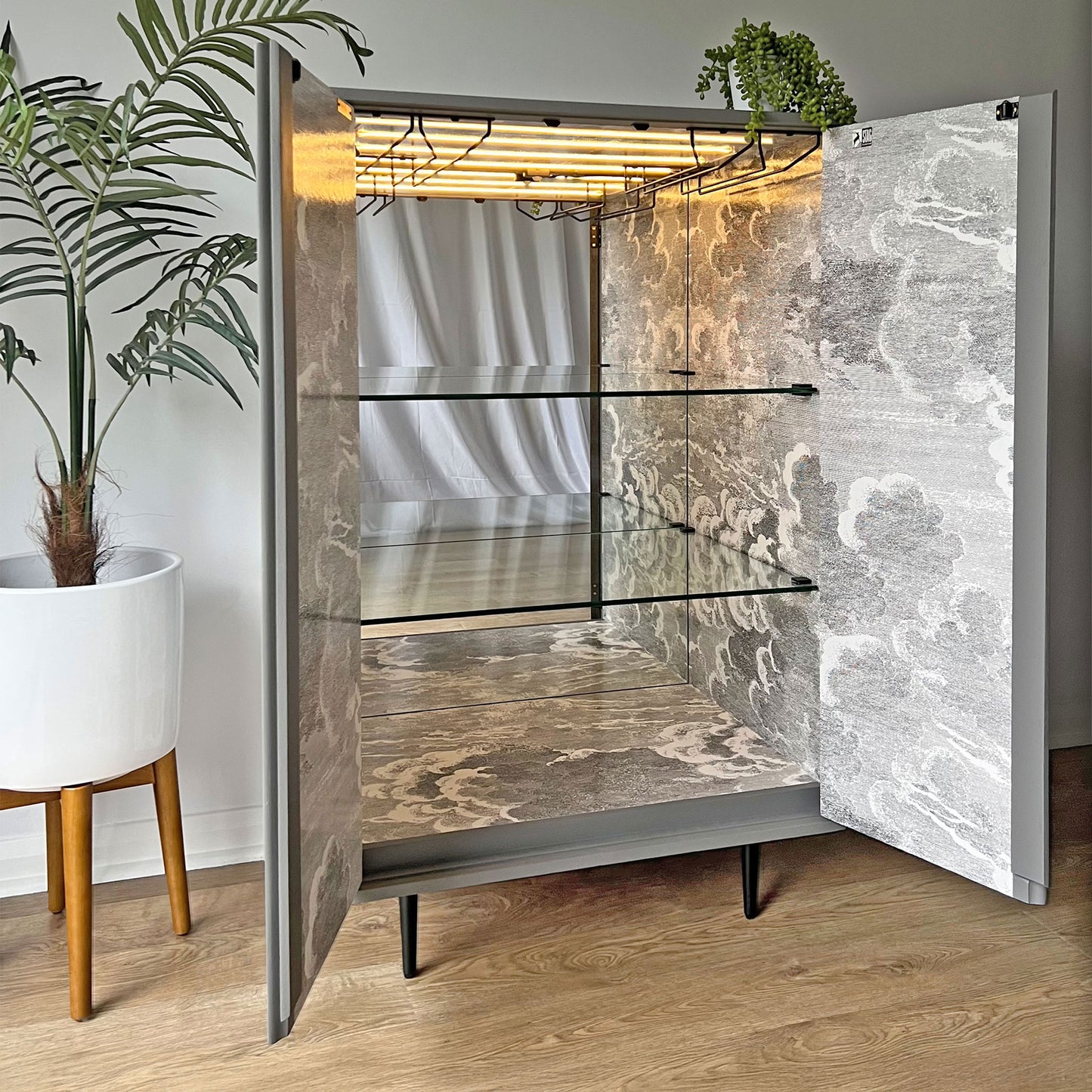 Motion sensor LED lighting inside bespoke drinks cabinet, illuminating fine spirits and glassware with a sophisticated touch.