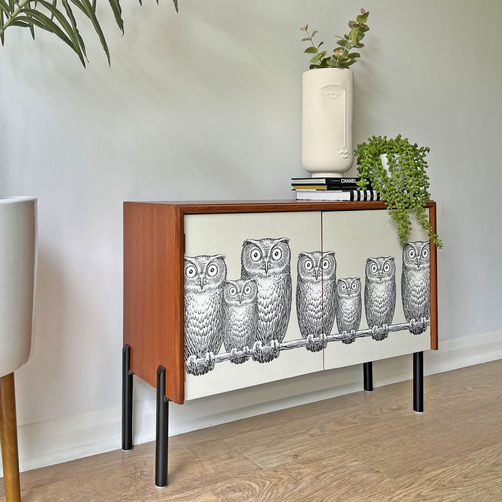 Side profile of G Plan cabinet, featuring a unique Fornasetti owl print, sleek matte black legs, and a clean, handle-less door design.