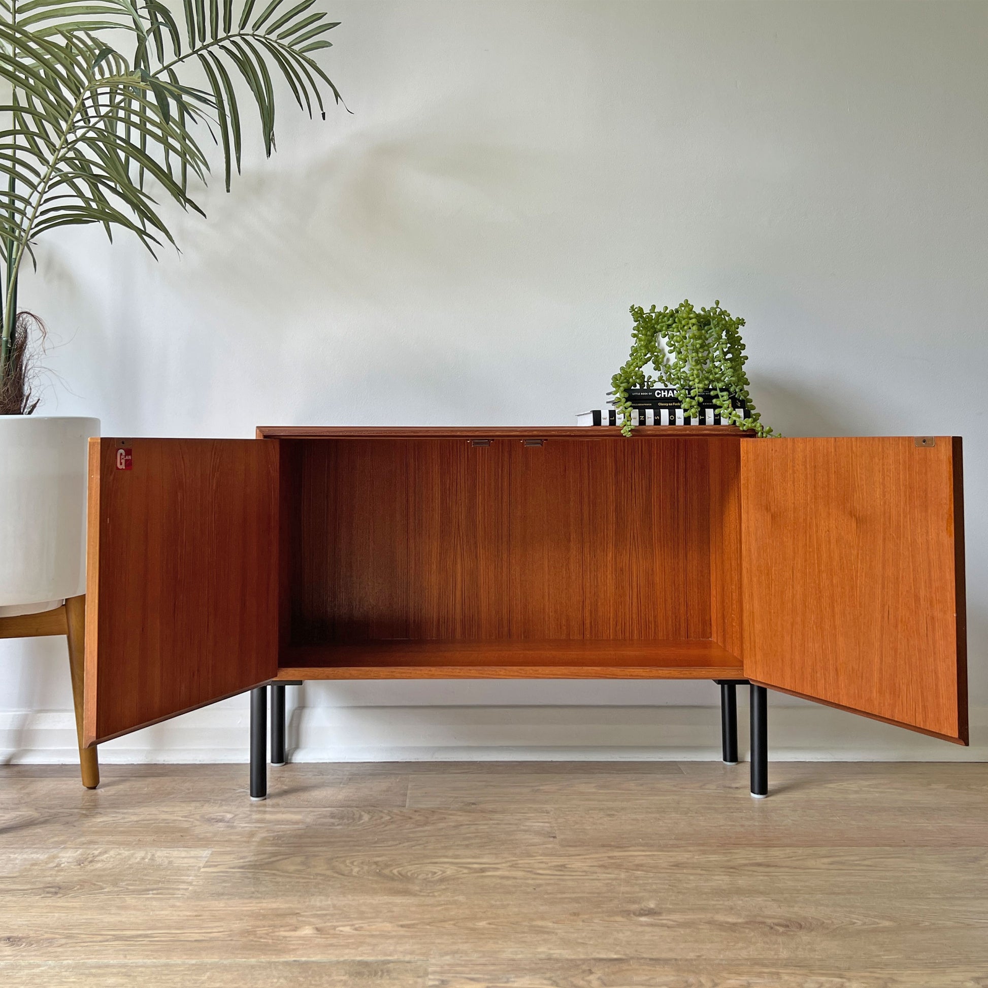 G Plan cabinet styled in a modern interior, serving as a statement piece with Fornasetti 'Nottambule' owl print and sleek black legs.