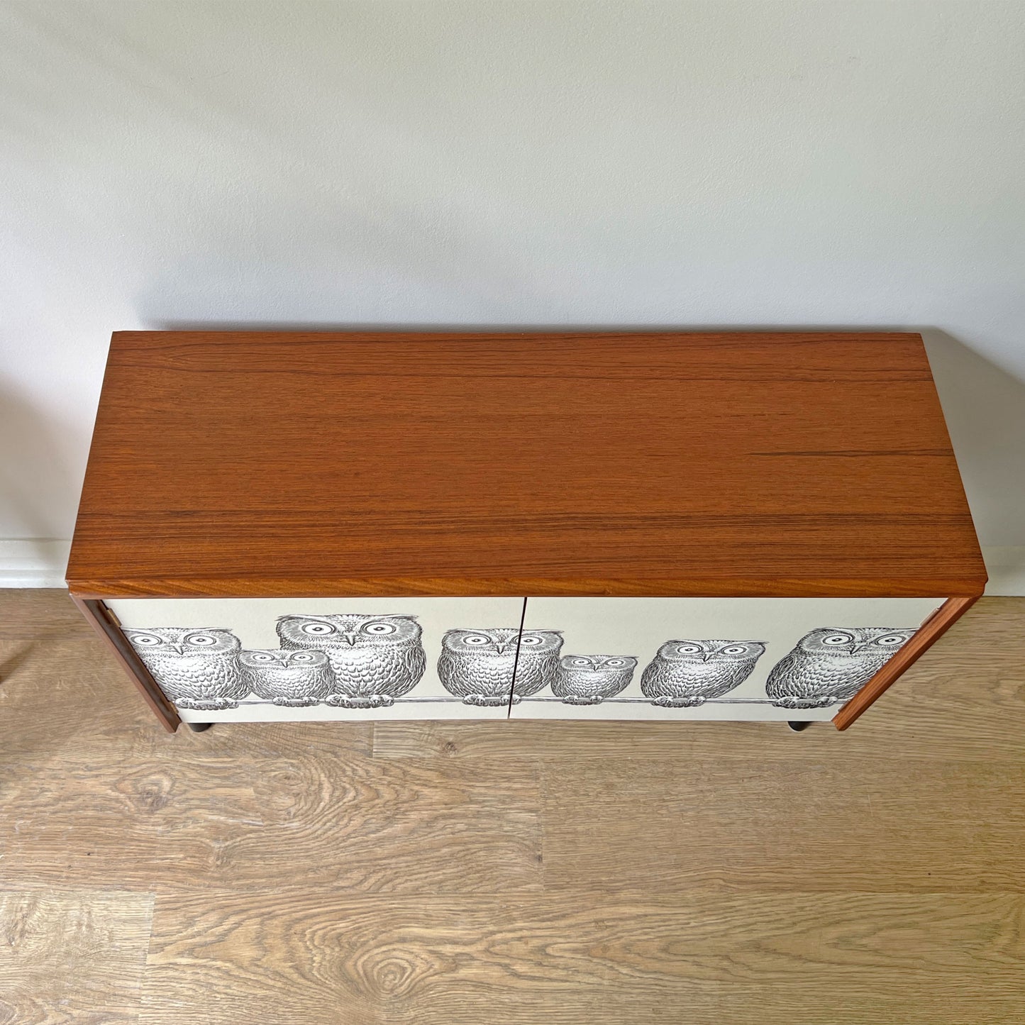 Top view of G Plan cabinet with smooth refinished surface, complementing the striking Fornasetti ‘Nottambule’ owl print.