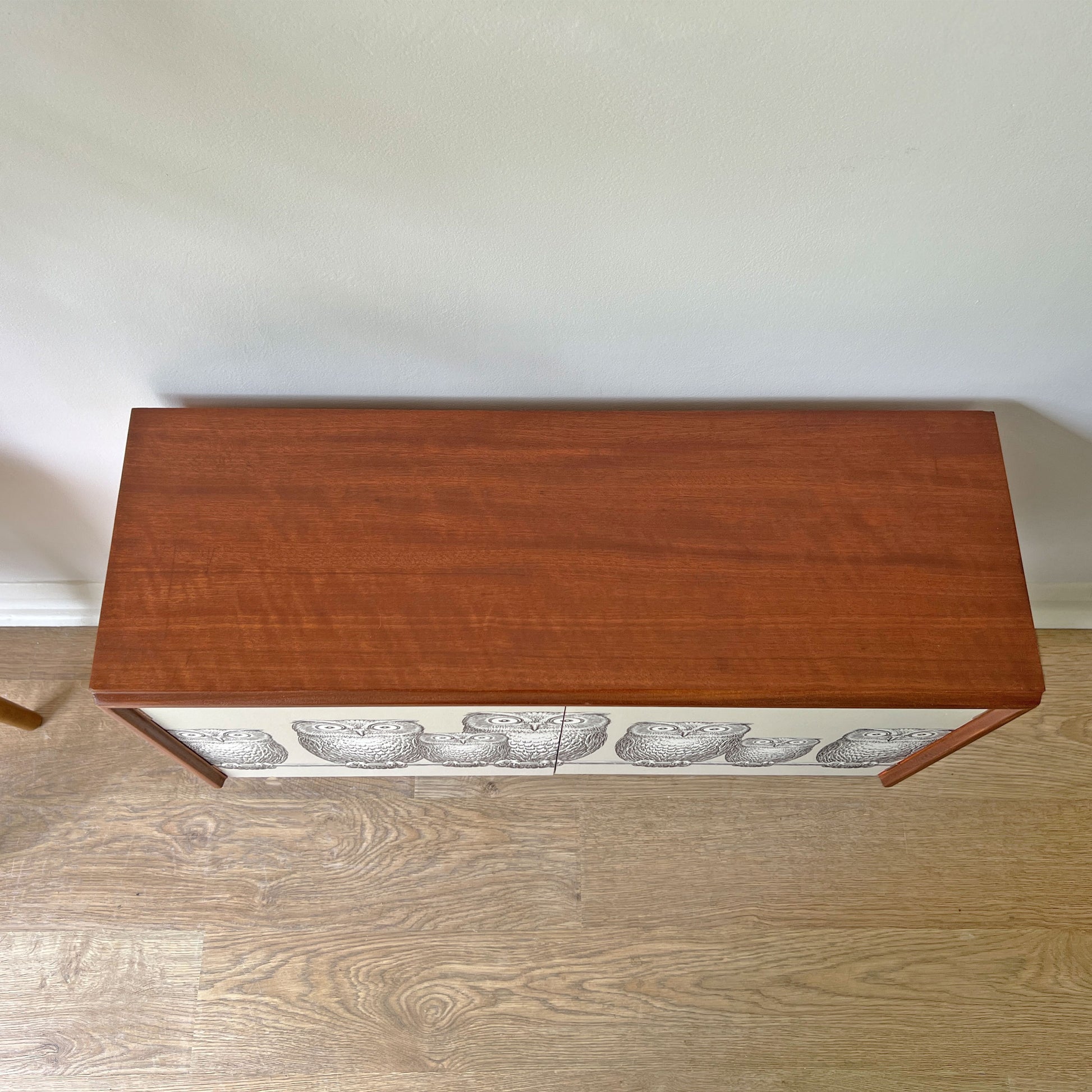 Top view of G Plan cabinet with smooth refinished surface, complementing the striking Fornasetti ‘Nottambule’ owl print.