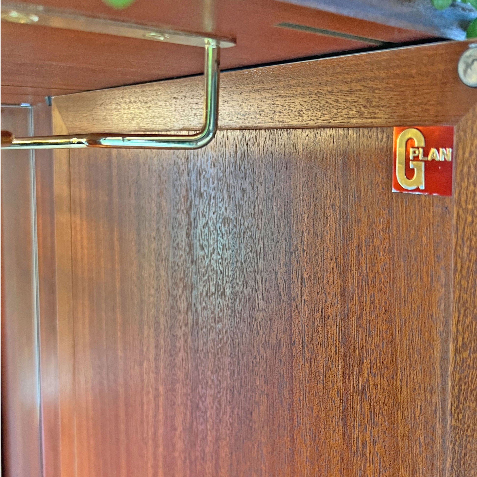 Brass glass racks inside G Plan drinks cabinet, offering stylish and practical storage for stemware and cocktail glasses