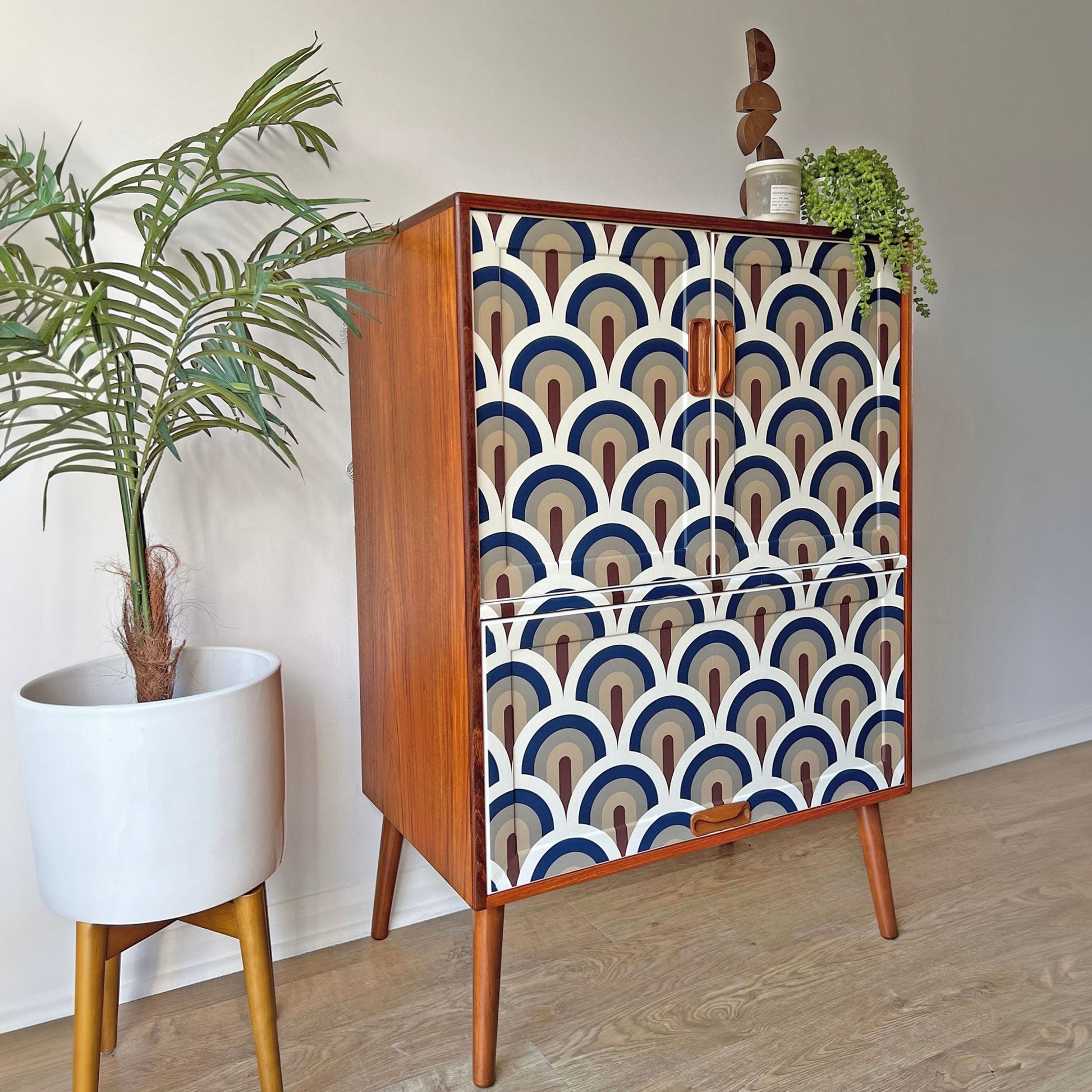 Side profile of G Plan drinks cabinet, highlighting its rich teak woodgrain, elegant brass accents, and contemporary decoupage doors.