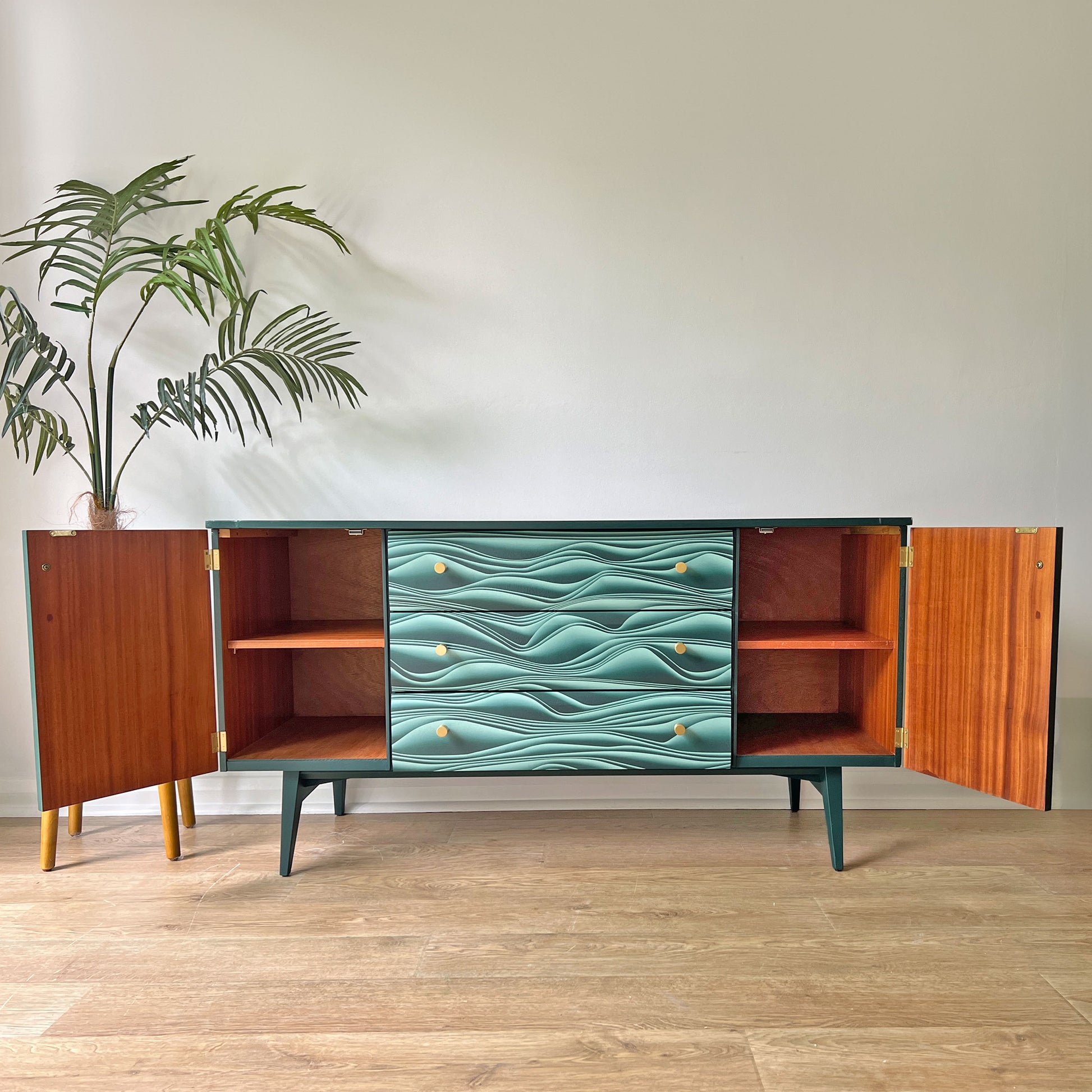 Refinished Meredew sideboard with revitalised wood interior, showcasing spacious storage with three drawers and a cupboard with fixed shelves.