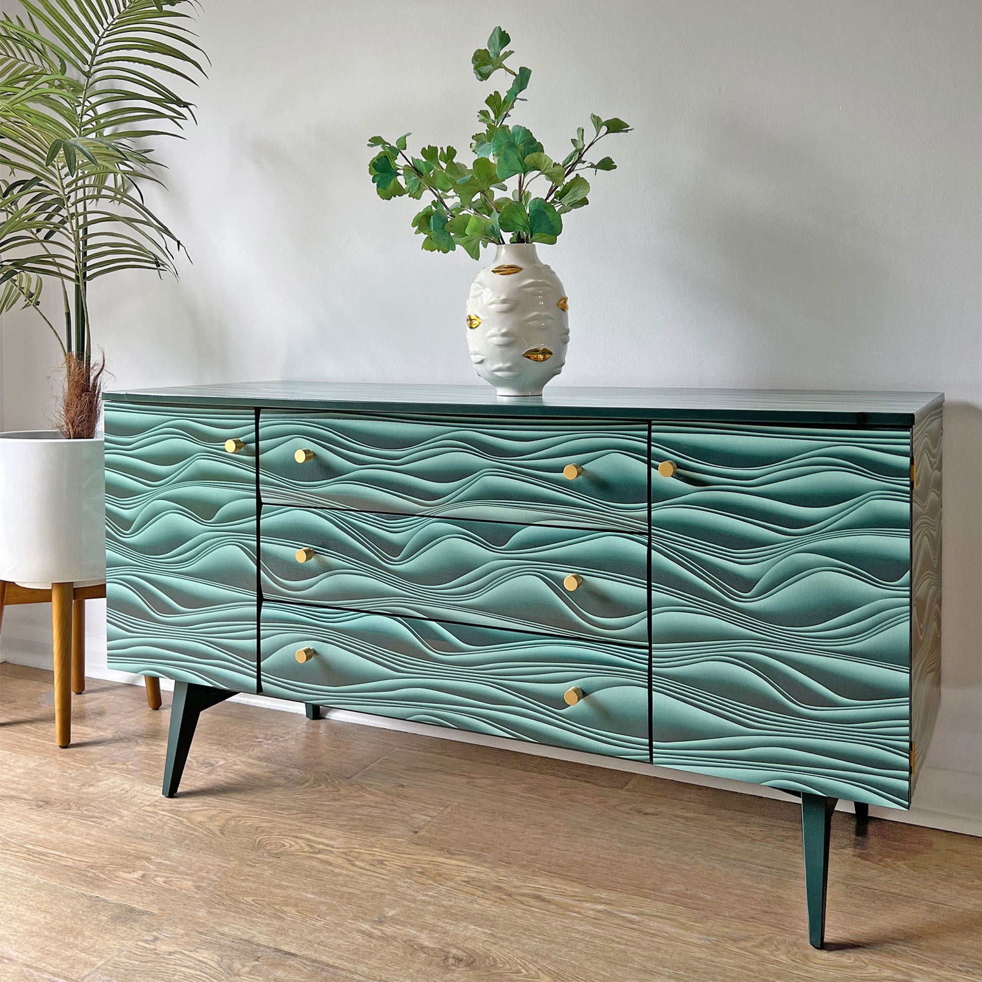 Side profile of Meredew sideboard, showcasing the bold Carmine Lake Marianas decoupage and sleek brass hardware.